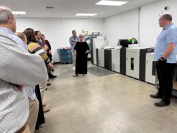 Photo showing Maggie Curry explaining the RISO VALEZUS Printer during the RevSpring CAC Meeting